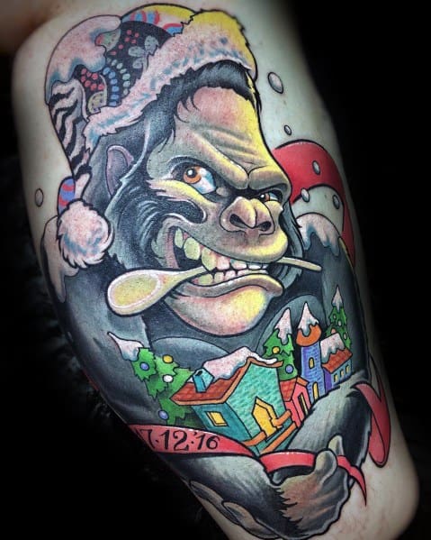 Christmas tattoo featuring a fierce gorilla wearing a Santa hat, holding a candy cane and a festive village scene, blending holiday cheer with a wild twist.