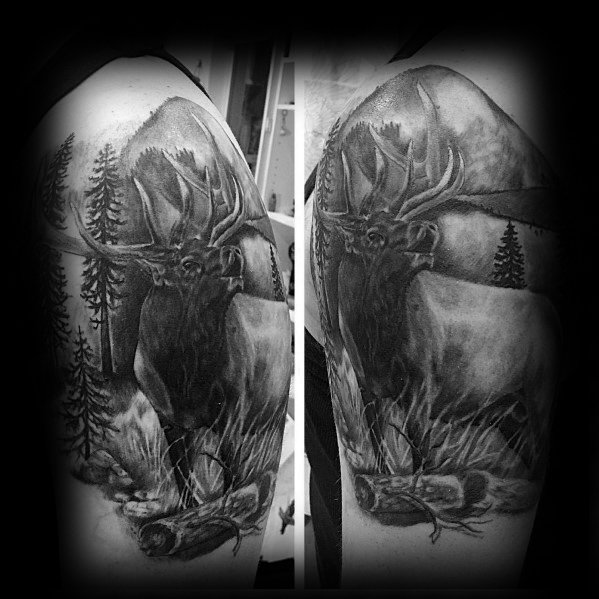 Realistic black and grey elk tattoo on the upper arm, featuring detailed shading, a mountain landscape, and forest elements for a bold nature-inspired design.