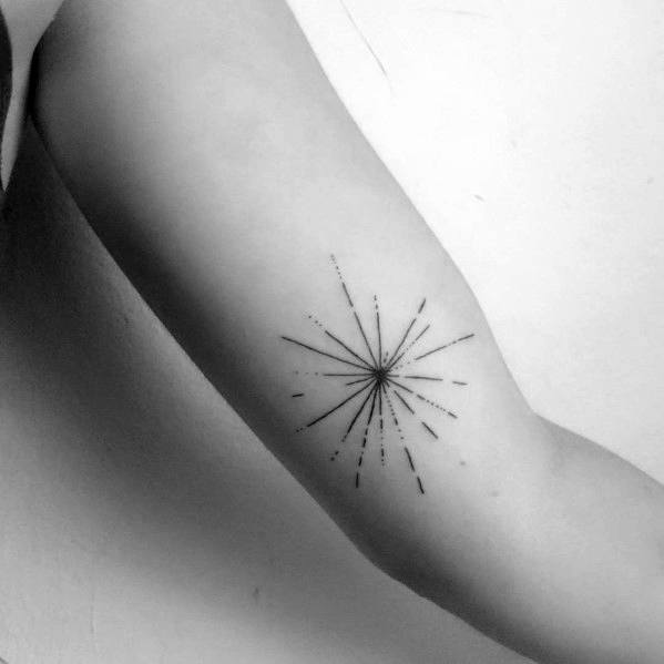 Minimalist black ink tattoo of a firework burst with fine lines and subtle dot detailing, placed on the inner arm for a delicate and elegant look.
