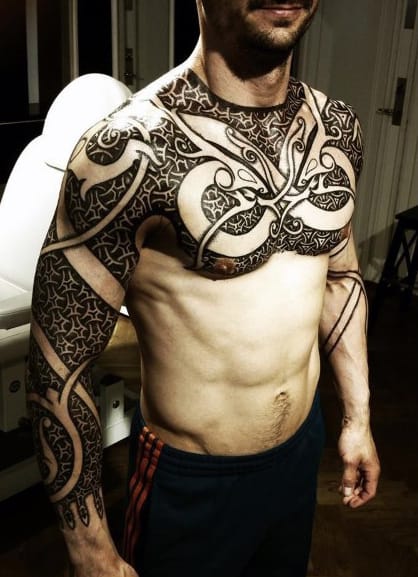 Man with intricate tribal tattoos covering his chest, shoulders, and arms