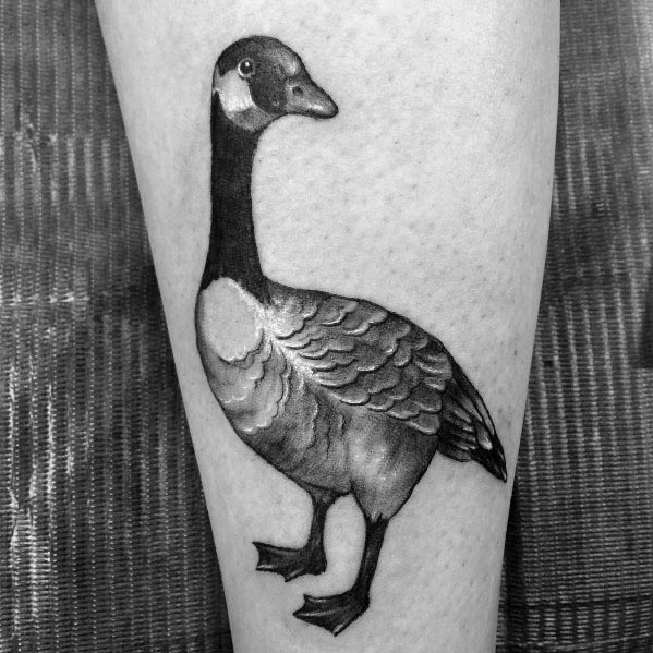 Realistic black and gray tattoo of a standing goose, inked on the leg with detailed shading and fine linework for a lifelike appearance.