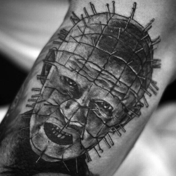 Black and grey *Hellraiser* tattoo of Pinhead with deep shading, intricate pin details, and a menacing expression for a bold horror design.