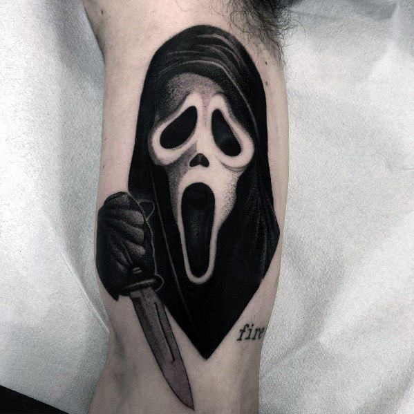 Black and grey tattoo of Ghostface from *Scream*, featuring the iconic mask, a hooded figure, and a knife for a bold and eerie horror design.