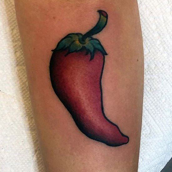 Bold red chili pepper tattoo with smooth shading and a green stem, creating a vibrant and classic design on the forearm.