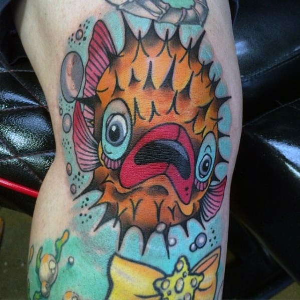 Vibrant pufferfish tattoo with exaggerated features, bold outlines, and underwater elements, creating a dynamic and expressive cartoonish design.