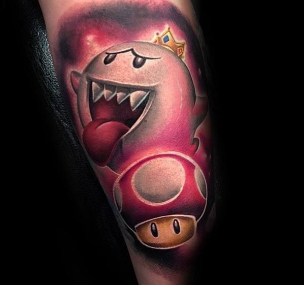 Mario-themed tattoo featuring King Boo with a golden crown and a Super Mushroom, inked with bold shading and a striking red and black background.