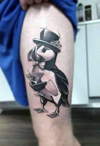 Black and grey tattoo of a dapper puffin wearing a top hat and bow tie, holding a martini glass. A charming and sophisticated design with fine details.