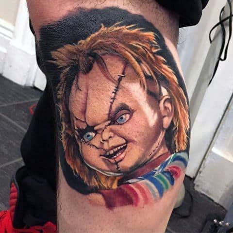 Realistic Chucky tattoo with vivid colors, featuring his stitched face, piercing blue eyes, and sinister grin for a bold horror-inspired design.