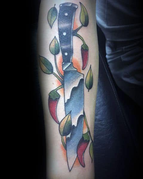 Tattoo of a sharp chef’s knife intertwined with chili peppers and leaves, featuring bold shading and vibrant colors for a dynamic culinary design.