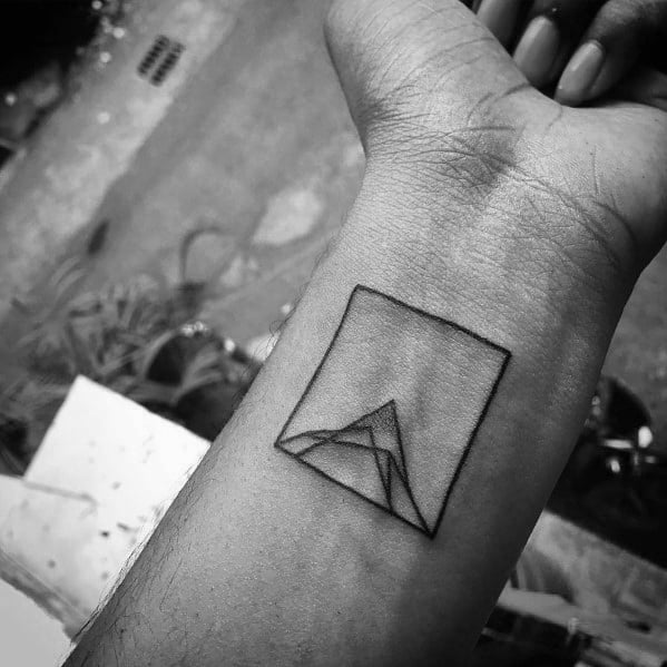 Minimalist geometric mountain tattoo on the wrist, featuring a simple outlined square with abstract angular peaks for a modern and artistic design.