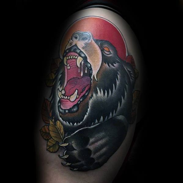 Neo-traditional bear tattoo on the upper arm featuring a roaring black bear, autumn leaves, and a bold red sun in the background.