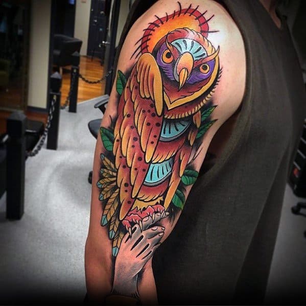 Neo-traditional owl tattoo with vibrant colors, a glowing halo, bold shading, and a symbolic hand, creating a striking upper arm design.