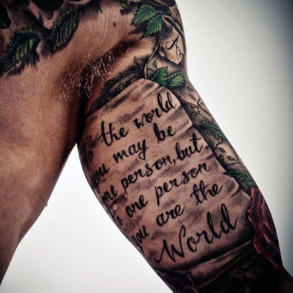 Close-up of an arm tattoo with text and decorative leaves surrounding it