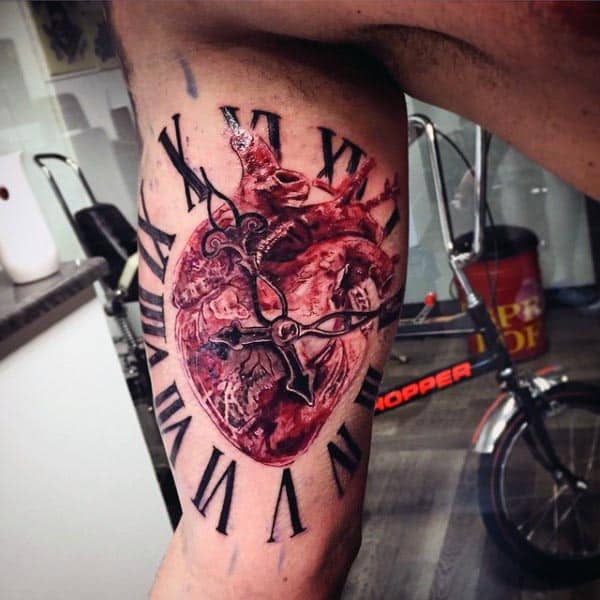 Realistic tattoo of an anatomical heart fused with a clock, featuring Roman numerals and clock hands, symbolizing time and life on the inner bicep