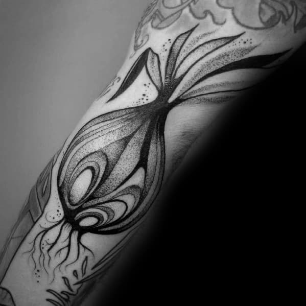 Abstract black and grey onion tattoo on the forearm, featuring bold lines, dot shading, and flowing organic shapes for a modern artistic look.
