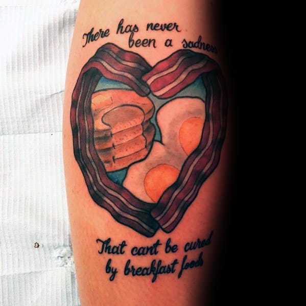 Heart-shaped breakfast tattoo featuring pancakes, eggs, and bacon, with the quote "There has never been a sadness that can't be cured by breakfast food."