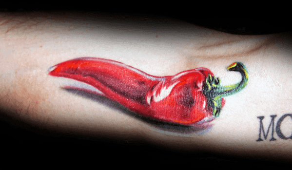 Hyper-realistic red chili pepper tattoo with glossy highlights and rich shading, creating a three-dimensional effect on the skin.