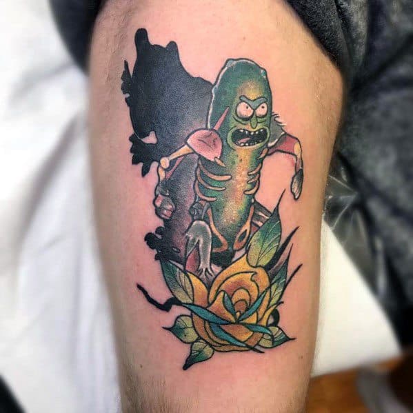 Pickle Rick cyborg tattoo with bold shading, dynamic pose, and a detailed yellow rose, creating a striking design on the upper arm.