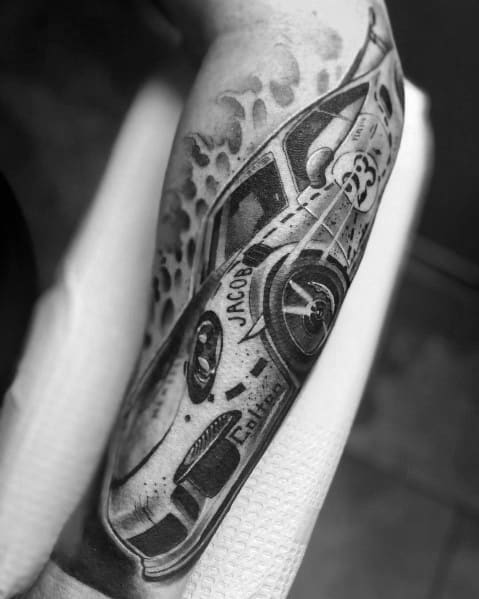 Detailed Porsche racing tattoo with dynamic angles, personalized lettering, and stylized smoke effects on the forearm.