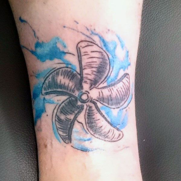 Black and grey ship propeller tattoo with blue watercolor-style waves, creating a dynamic nautical design with bold shading and movement effects.