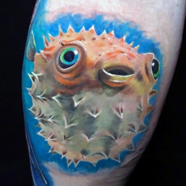 Hyper-realistic pufferfish tattoo with detailed textures, lifelike shading, and a vibrant blue underwater background, creating a striking 3D effect.
