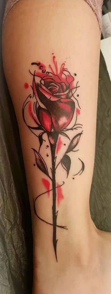 Bold and artistic tattoo of the enchanted rose with a sketch-style design, featuring deep red hues, splashes of ink, and abstract elements.