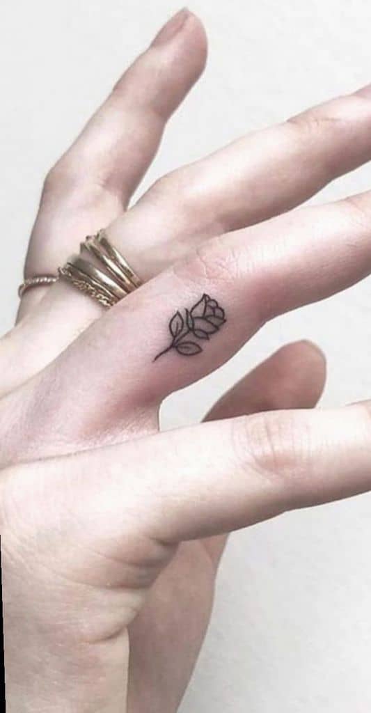 Minimalist fine-line rose tattoo on the side of a finger, symbolizing the enchanted rose from Beauty and the Beast.