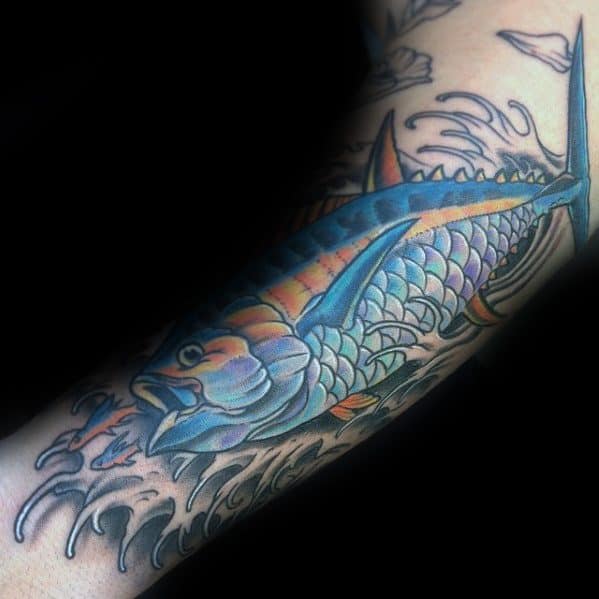 Colorful tattoo of a leaping salmon with intricate scales and dynamic waves, featuring bold blue and orange tones for a vibrant and energetic forearm design.