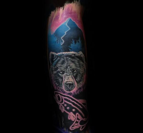 Vibrant tattoo of a bear and salmon under a glowing mountain sky, featuring bold colors and intricate shading for a mystical and nature-inspired sleeve design.