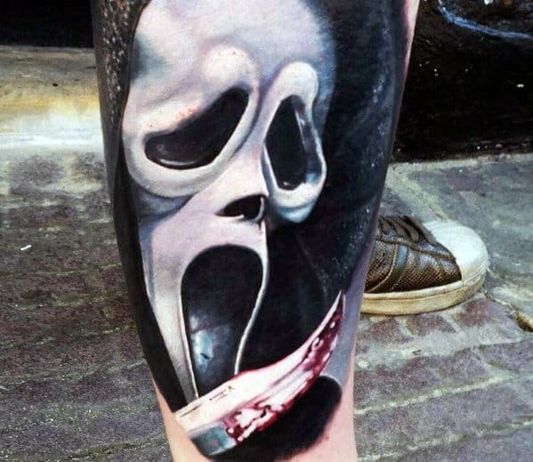 Realistic color tattoo of the Ghostface mask from *Scream*, featuring eerie shading and a bloodied knife for a chilling and intense horror design.