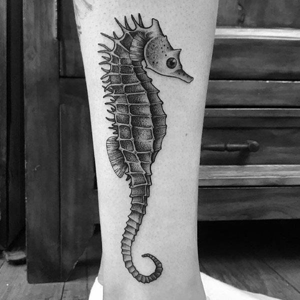Black and grey seahorse tattoo on leg, featuring fine linework, detailed shading, and a realistic texture for a classic and elegant marine design.