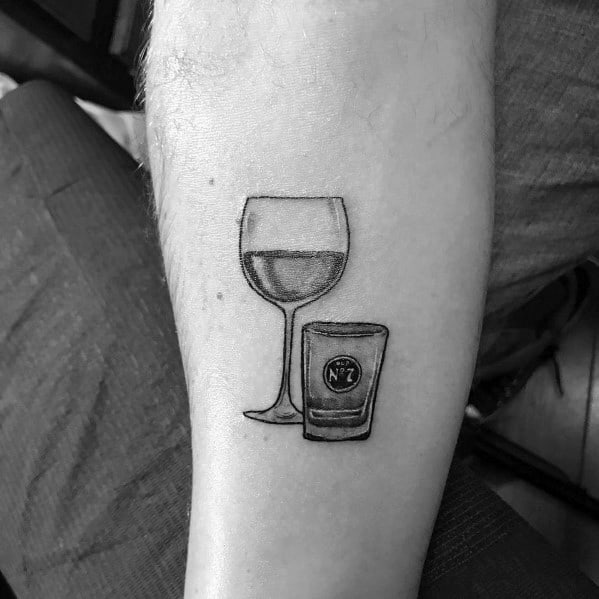 Minimalist black and grey tattoo featuring a wine glass and a shot glass with a "No. 7" label, symbolizing a contrast between elegance and boldness.