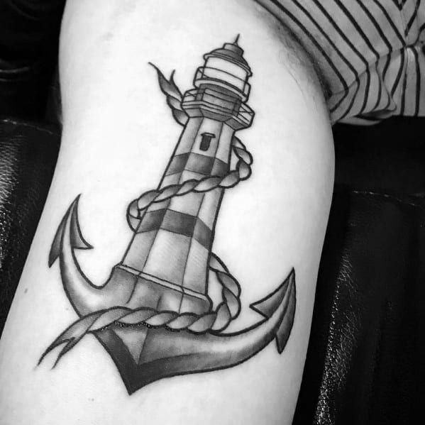 Black and gray lighthouse and anchor tattoo with detailed shading and a rope wrapped around, symbolizing guidance, stability, and maritime strength.