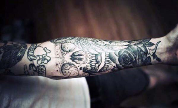 Tattooed arm displaying a detailed skull, rose, and various other intricate designs