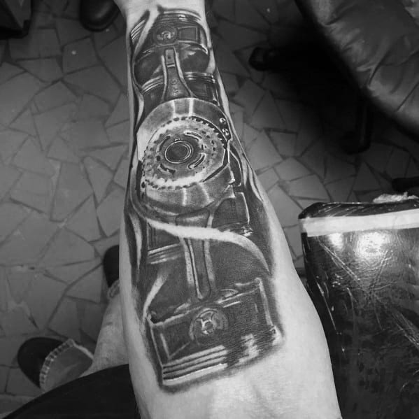 Realistic black and grey Subaru-themed sleeve tattoo featuring detailed pistons, gears, and mechanical components, symbolizing the iconic boxer engine.