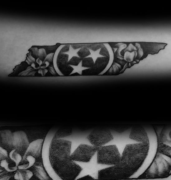Black and grey Tennessee state-shaped tattoo featuring the three-star emblem with floral accents, blending state pride with a decorative touch.