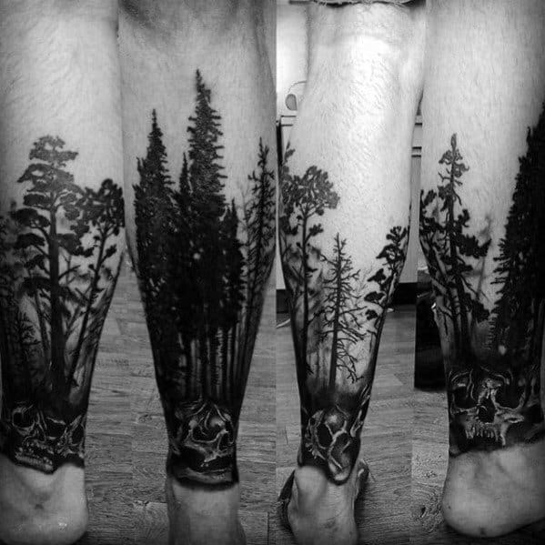 Black ink forest tattoo on the leg, featuring tall pine trees fading into the skin with skull details at the base for a dark, mysterious design.