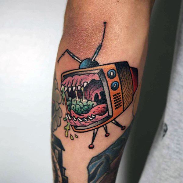Colorful tattoo of a vintage TV with monstrous, sharp teeth and a slimy, dripping tongue, blending horror and surrealism with bold lines and shading.