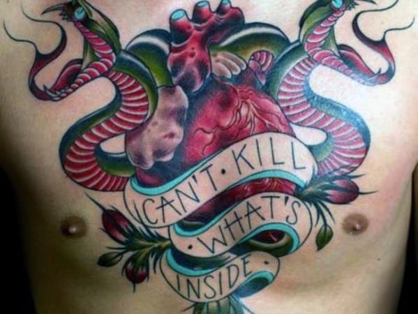 Vibrant two-headed snake tattoo on the chest, wrapped around an anatomical heart with a banner reading "Can't Kill What's Inside" for a bold design.