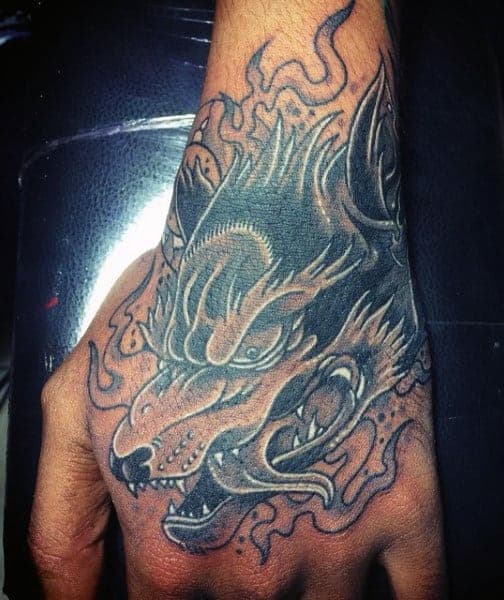 A wolf tattoo with blazing, fiery details adorns the hand