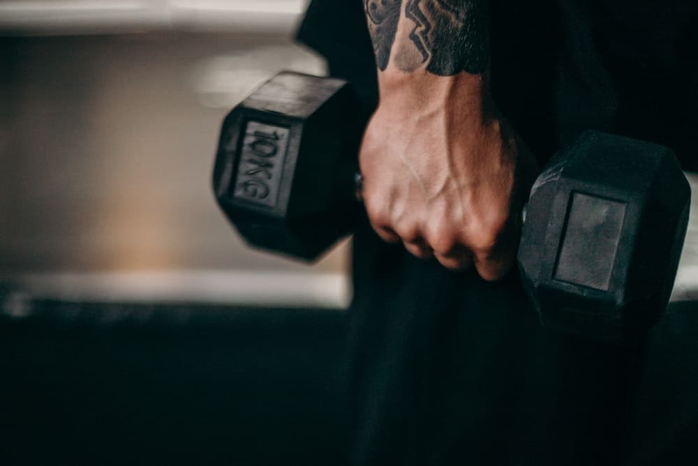 tattooed hand holds a 10kg dumbbell