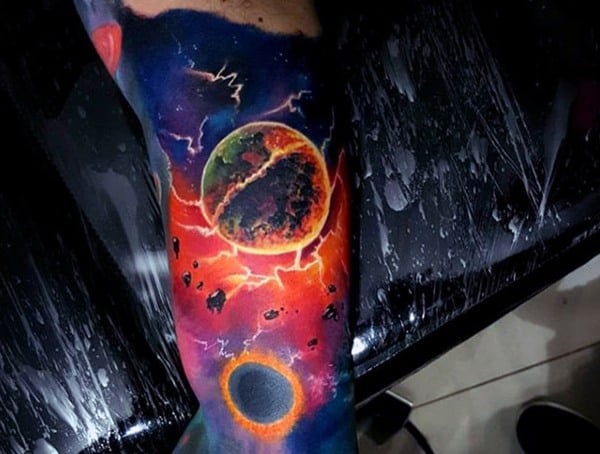 Colorful space-themed tattoo depicting planets, lightning, and cosmic elements on an arm