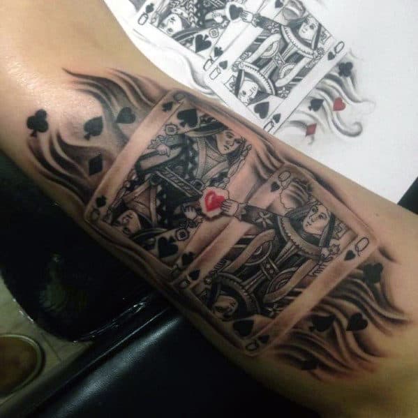 Playing card tattoo of the Queen of Spades with flaming edges and a red heart