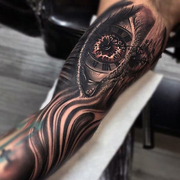 Tattoo of a detailed, surrealistic eye and clock on a person's leg