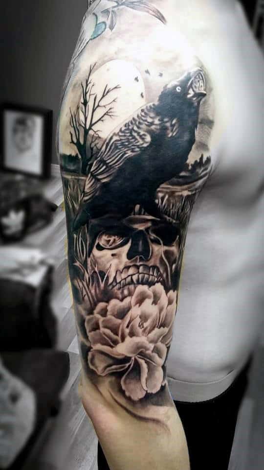 Black and gray tattoo sleeve featuring a crow, skull, and rose on a person's arm
