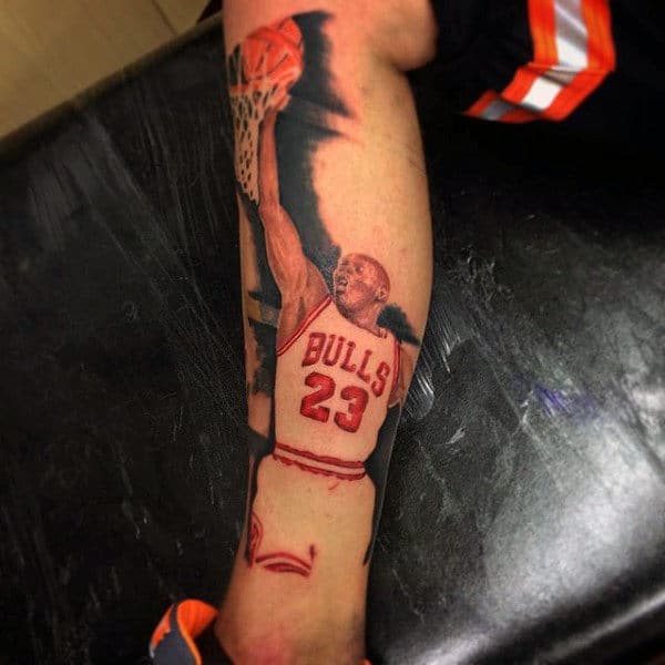 Tattoo of basketball player in a Bulls jersey with number 23, dunking a ball on forearm