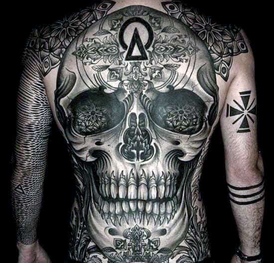 Person with an intricate, full-back skull tattoo and additional arm tattoos