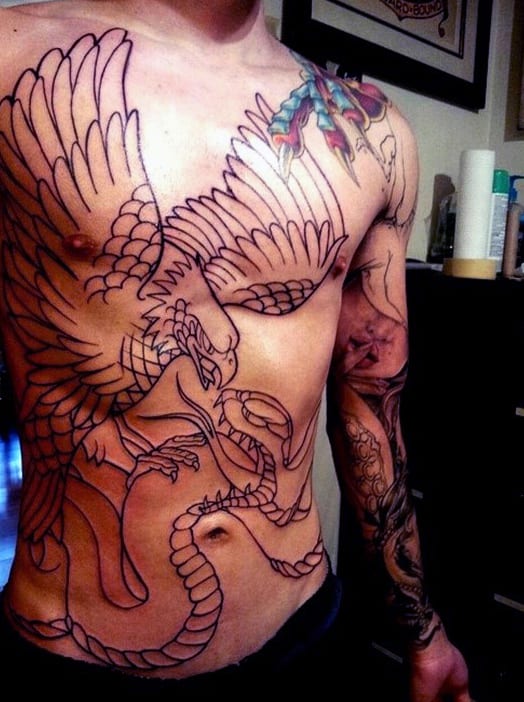 Man with an intricate eagle and snake tattoo outlines on his chest and arm sleeves