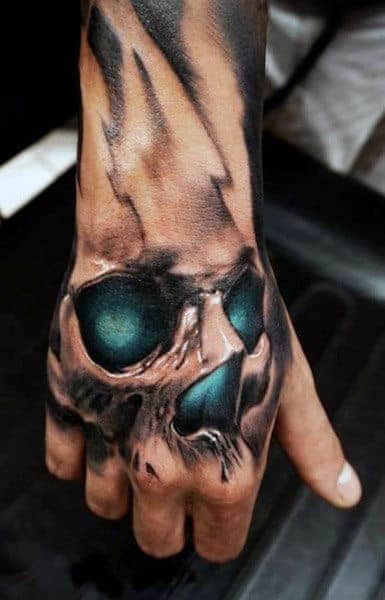 Tattoo of a skull with dark shading on the back of a person's hand