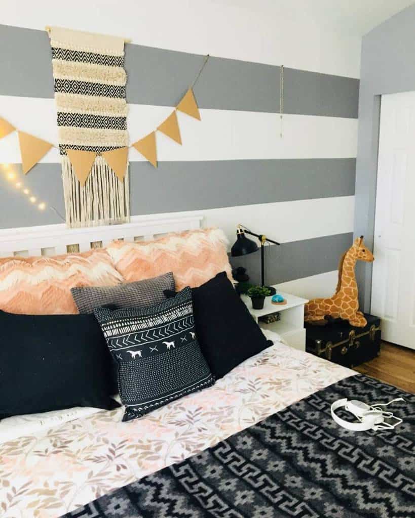Striped bedroom with wall tapestry, hanging flags, giraffe toy, and patterned bedding.